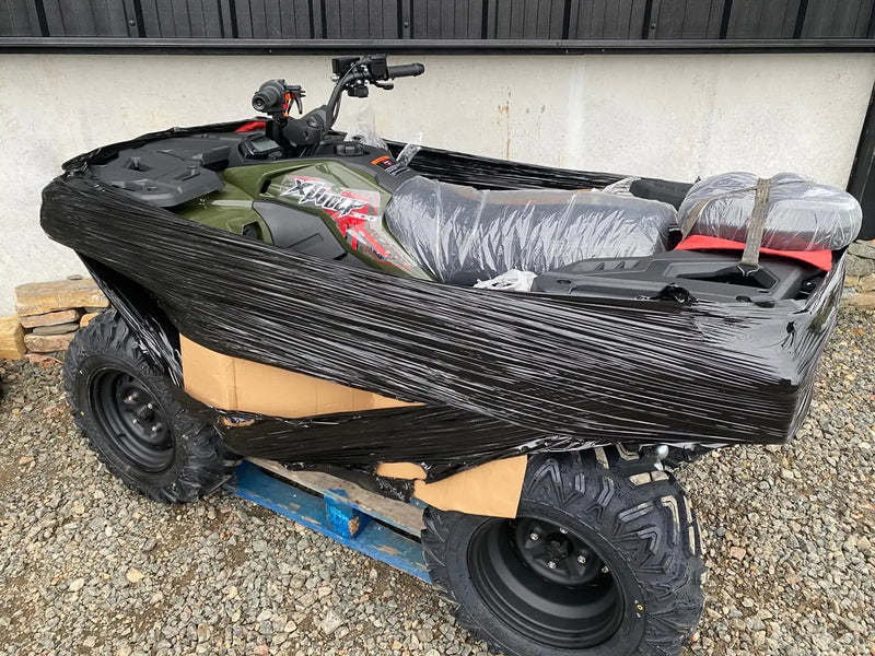 Green and red yamaha xplorer atv wrapped in black plastic.