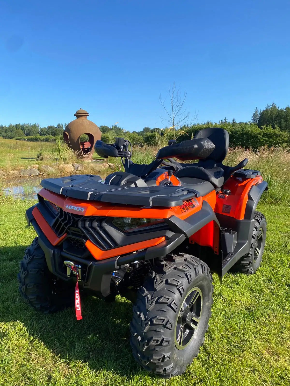 Orange and black can-am outlander atv with rugged tires and a protective front bumper.