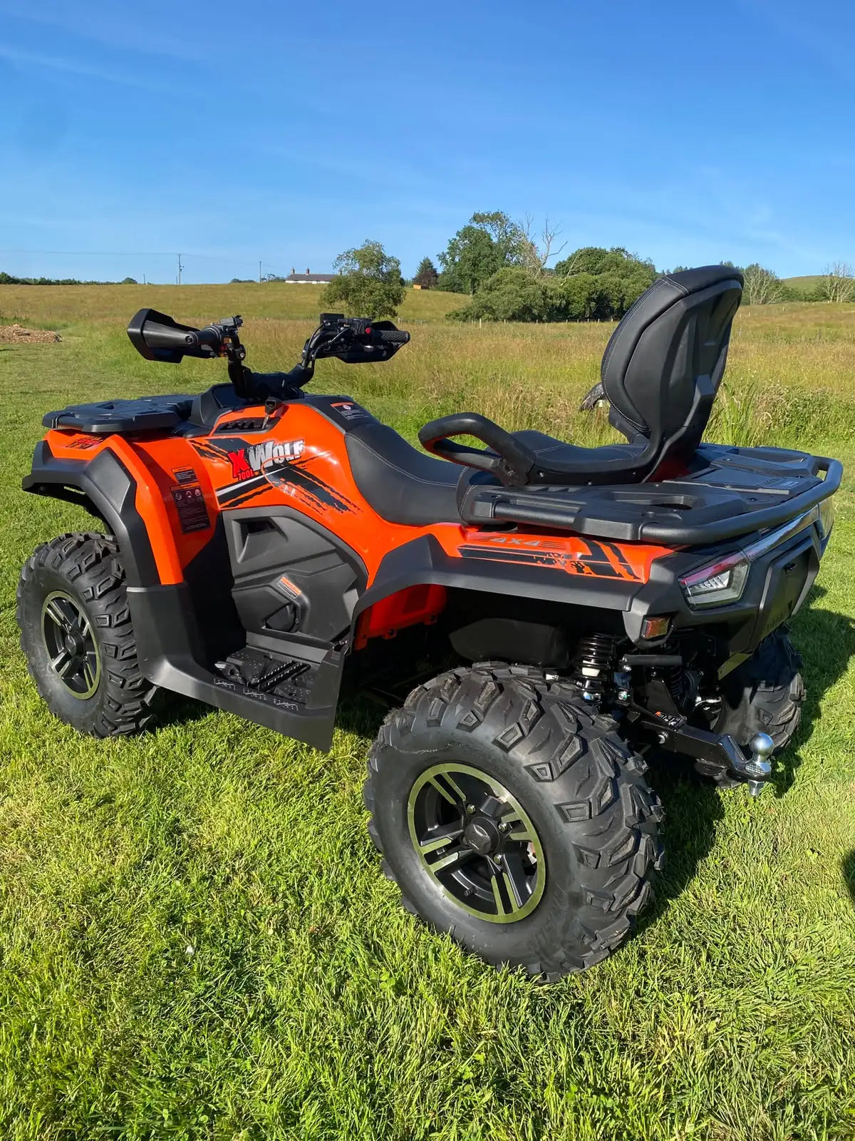 Orange and black can-am outlander atv with rugged tires and a rear cargo rack.
