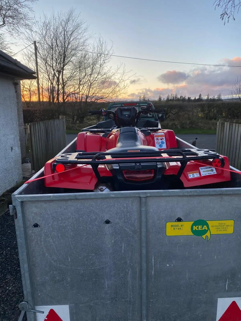 Red atv with black seat and handlebars, featuring a rear rack and safety stickers.